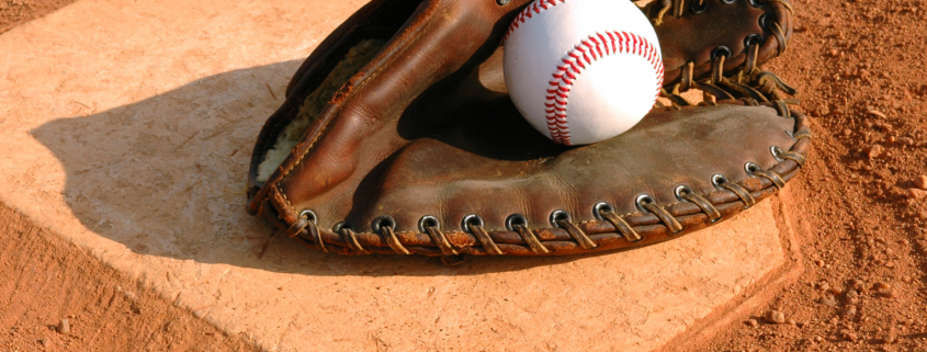 Baseball inside a baseball glove on top of home plate.